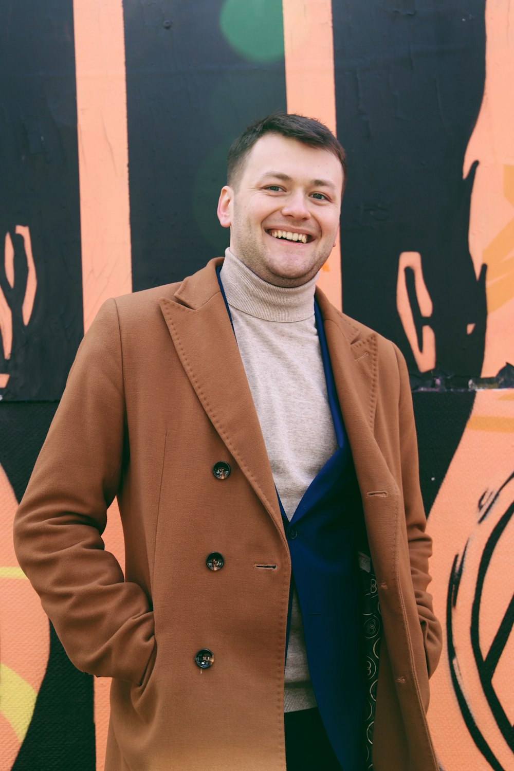 man in brown coat standing near wall