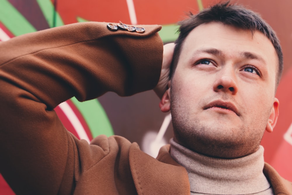 man in brown sweater lying on green and red inflatable ring