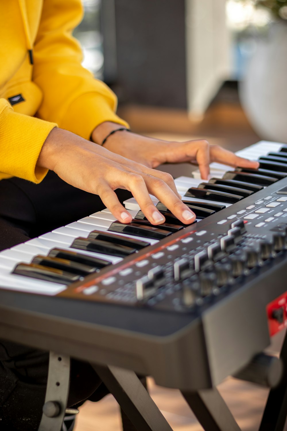 person in yellow long sleeve shirt playing black and white electric keyboard
