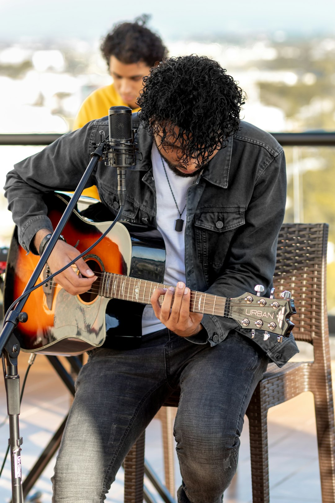 man in blue denim jacket playing brown acoustic guitar