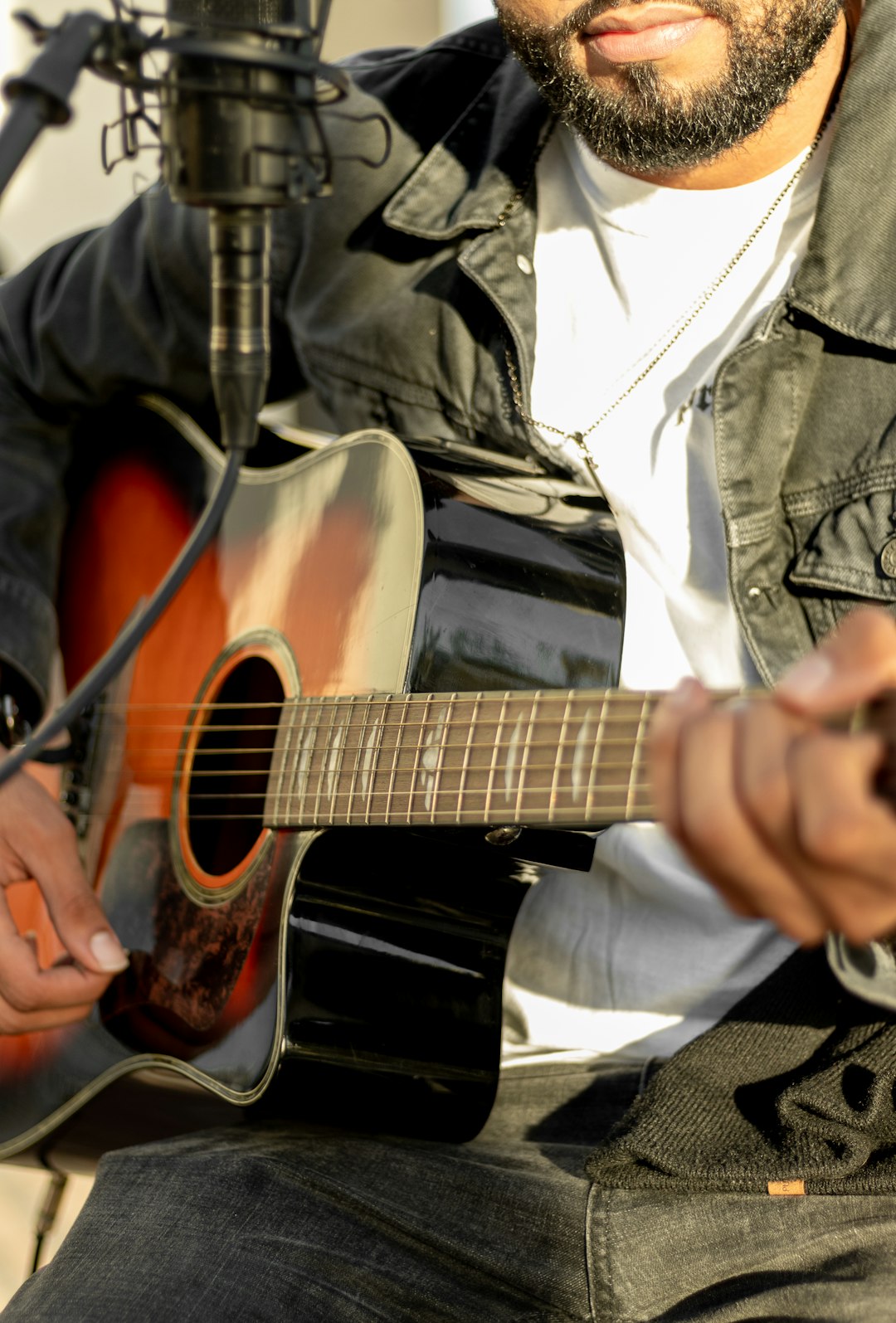 man in gray jacket playing acoustic guitar