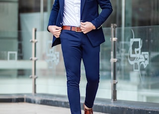 man in blue suit standing on sidewalk during daytime