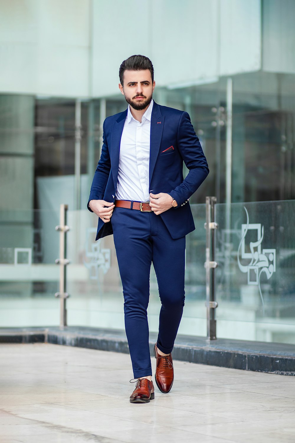 Hombre en traje azul de pie en la acera durante el día