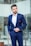A well-dressed man in a stylish suit standing confidently in an urban setting.