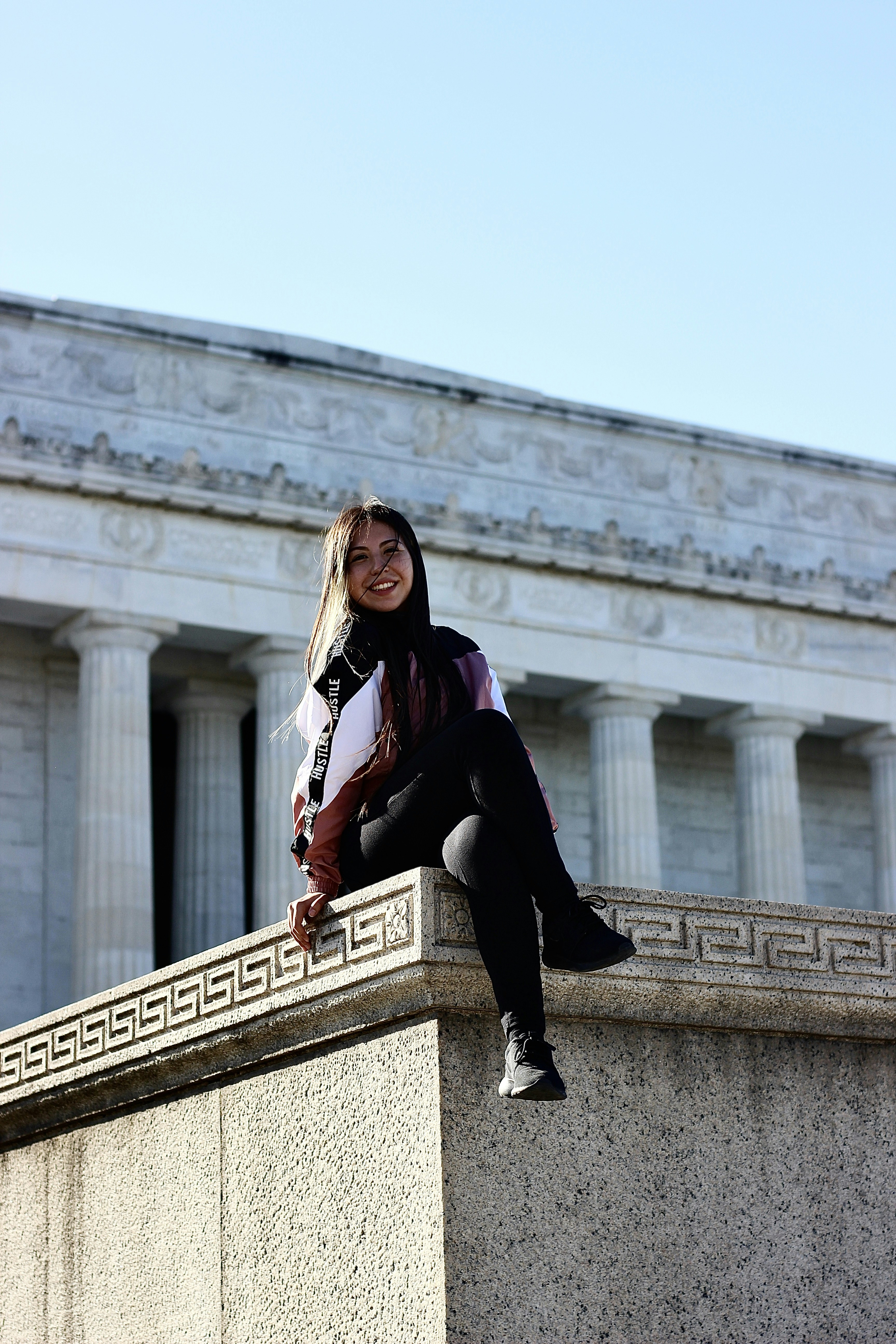 Frau in schwarzer Jacke sitzt tagsüber auf einer Betonbank