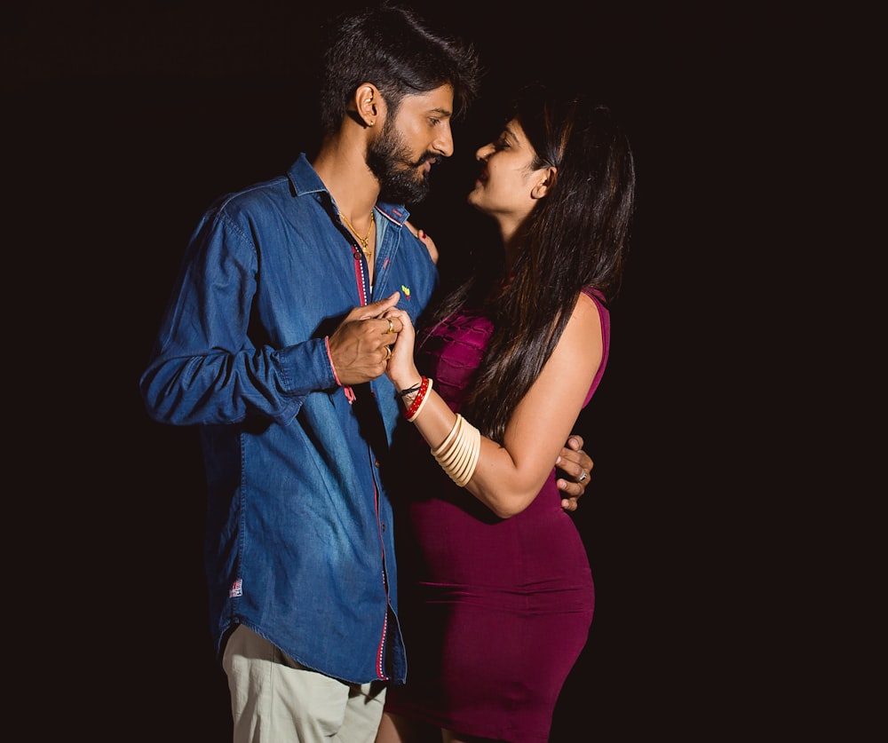 man in blue dress shirt kissing woman in red dress