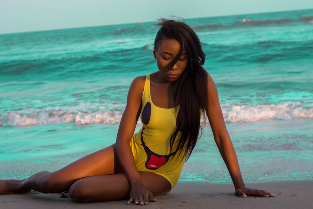 woman in yellow and black one piece swimsuit standing on beach during daytime