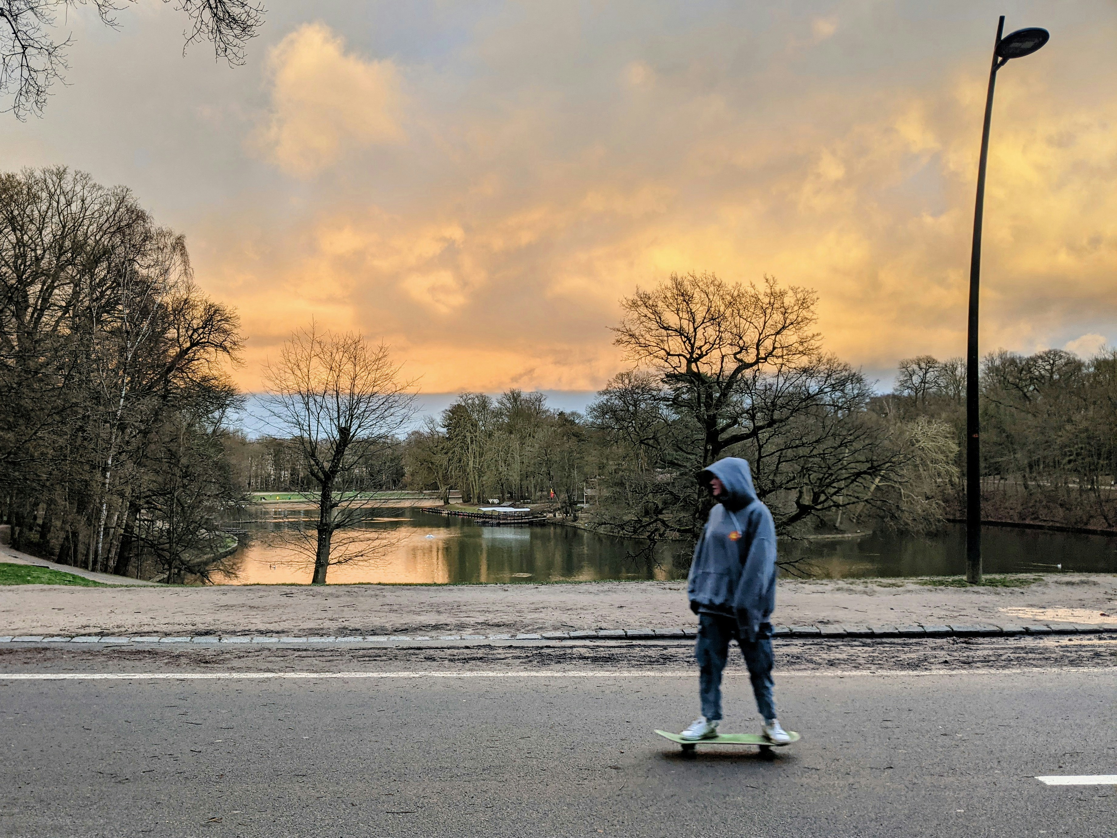 man in blue jacket standing on gray concrete road near body of water during daytime