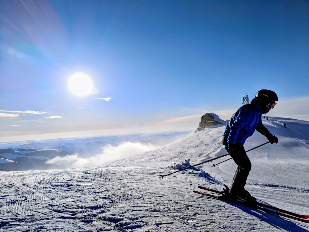 man in blue jacket and black pants standing on snow covered mountain during daytime