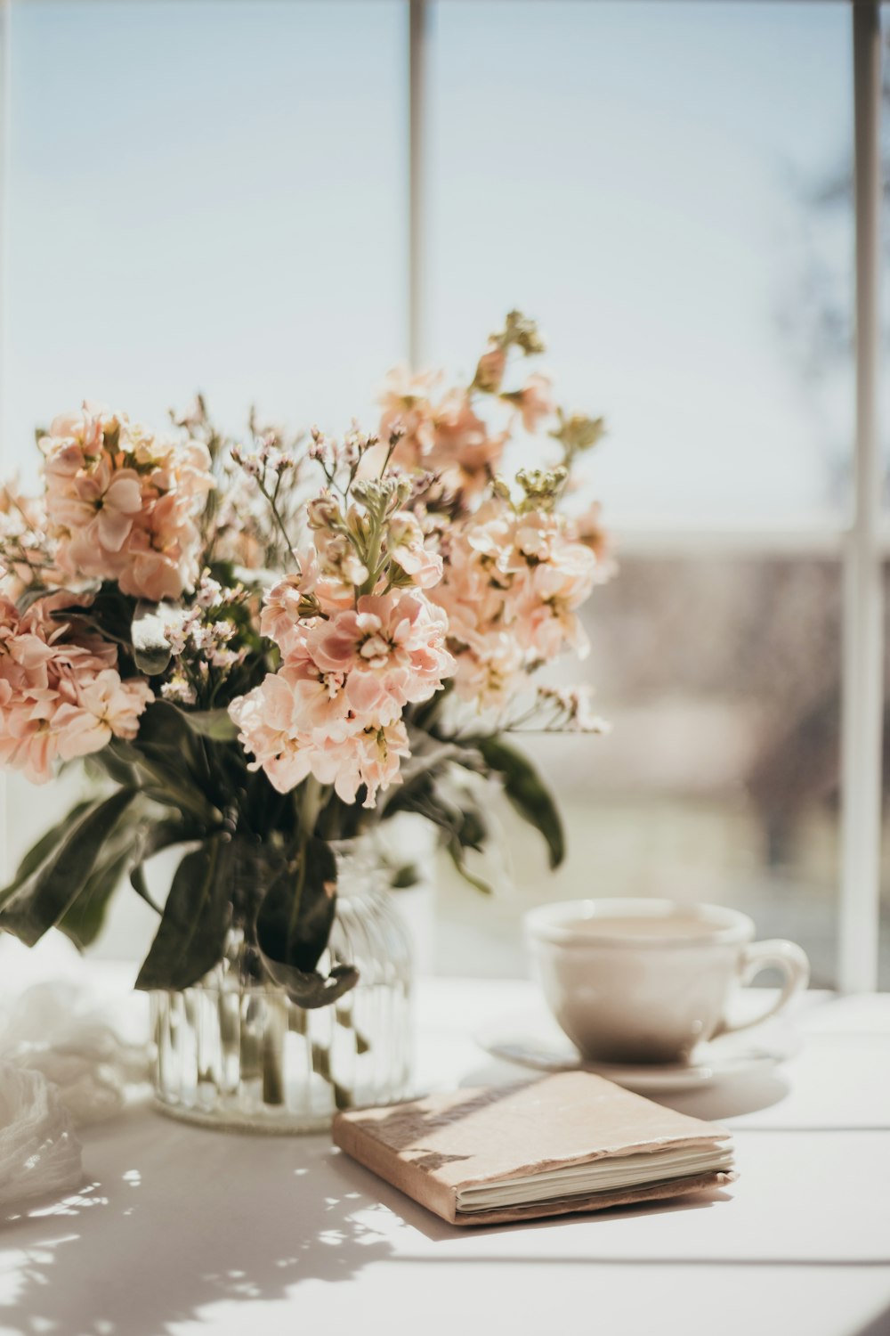 白いテーブルの上の白い陶器の茶碗の上の白とピンクの花