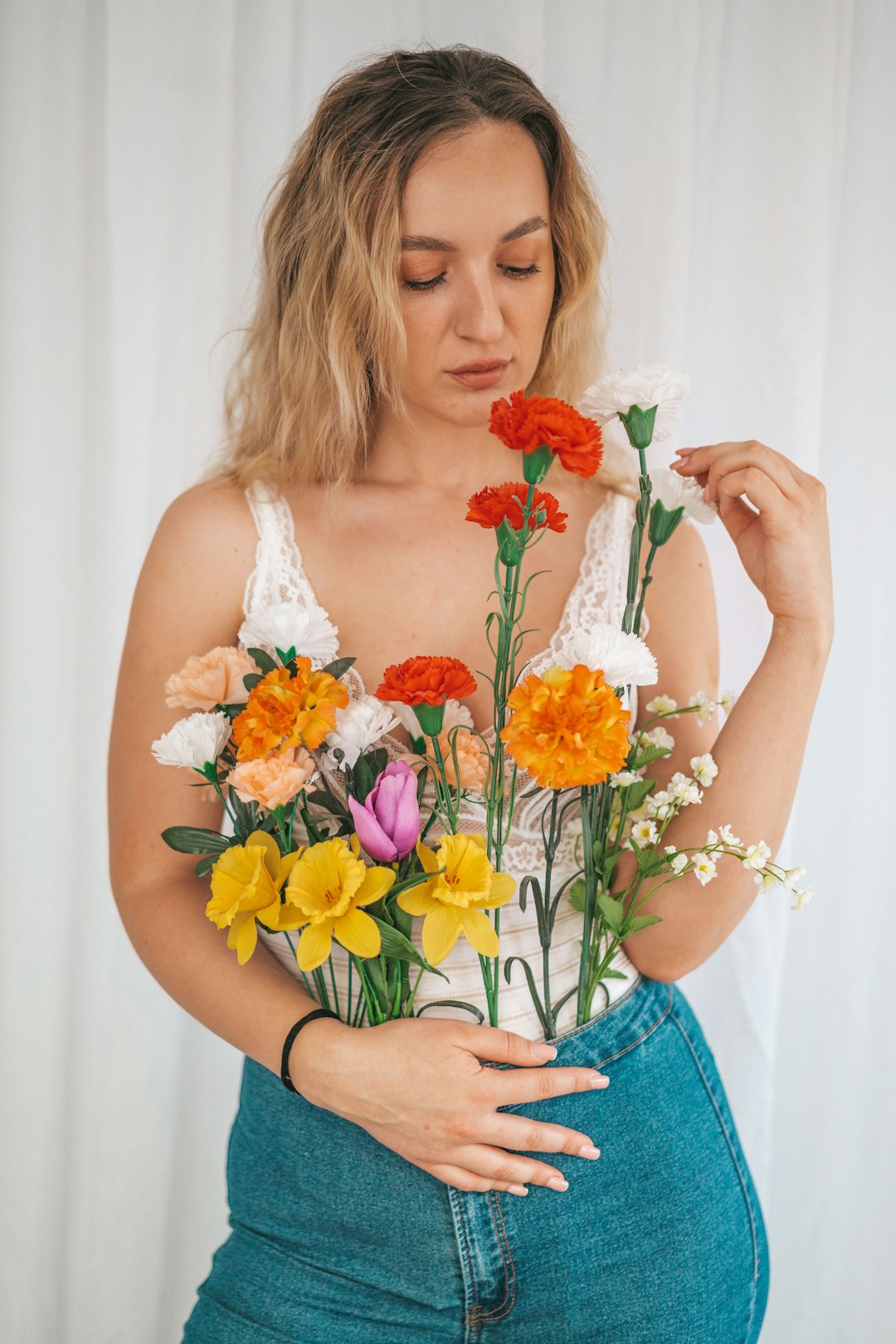 woman in white tank top holding bouquet of flowers