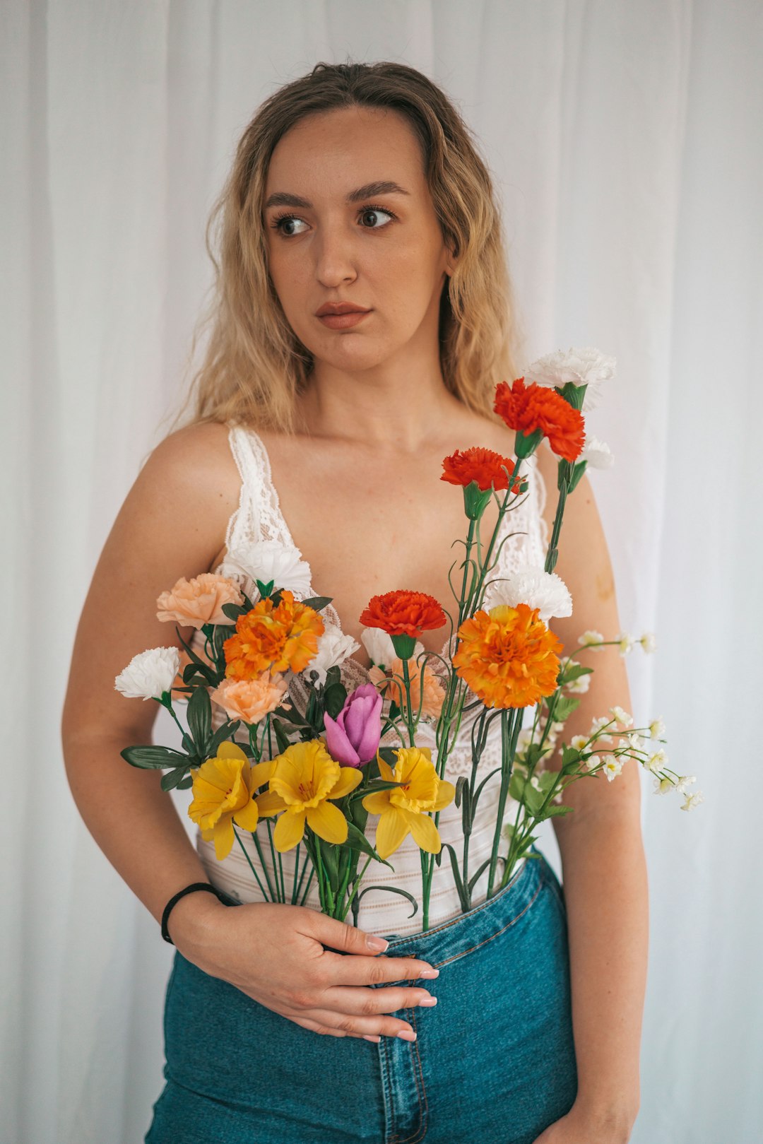 woman in white tank top holding bouquet of flowers