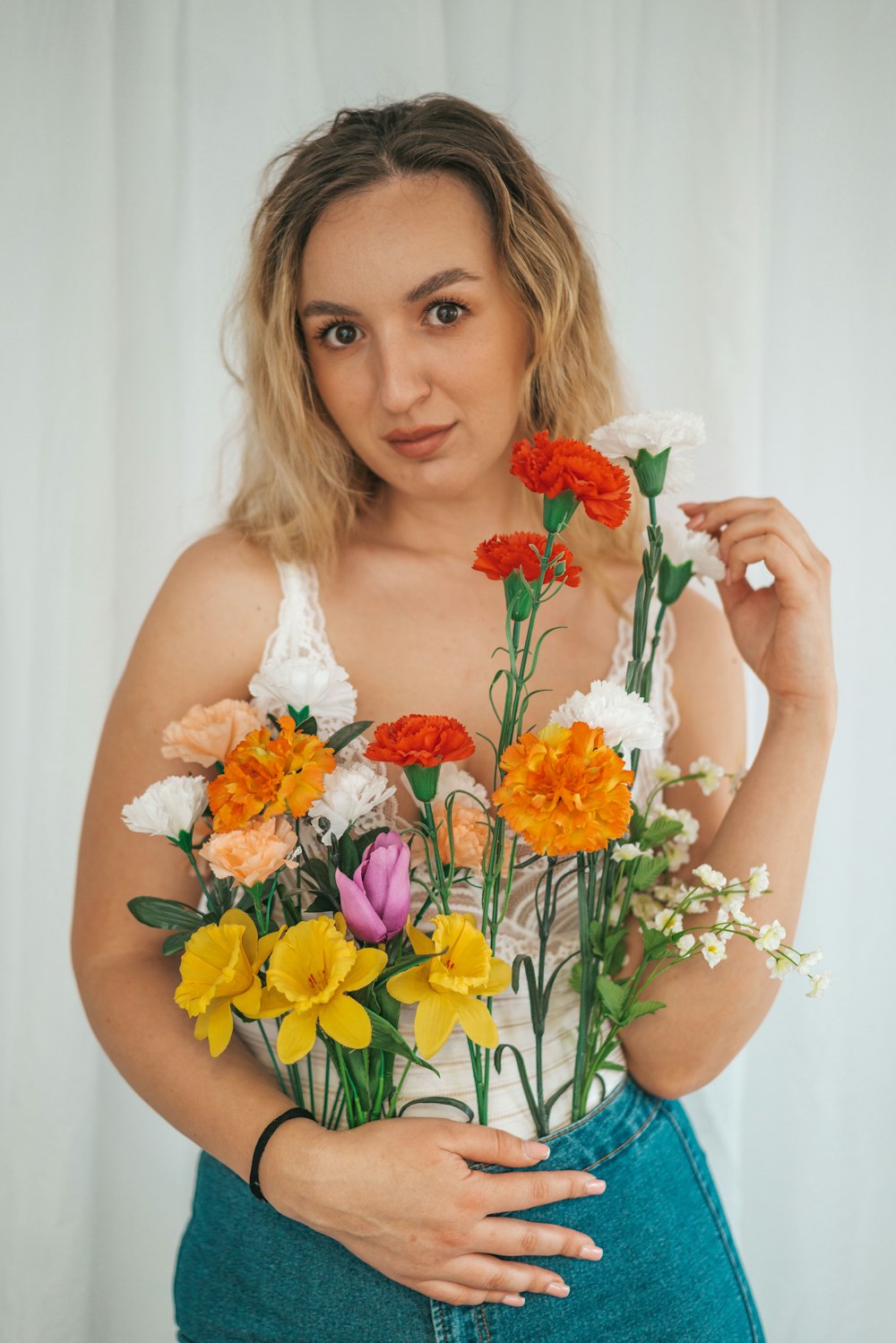 woman in white tank top holding orange and white flower bouquet