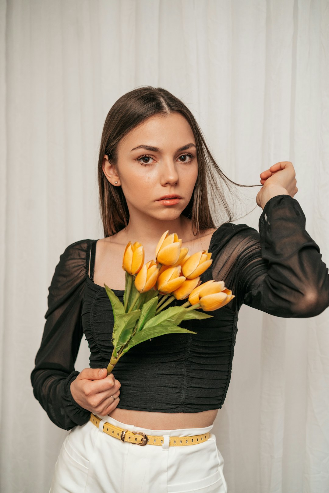 woman in black long sleeve shirt holding yellow tulips