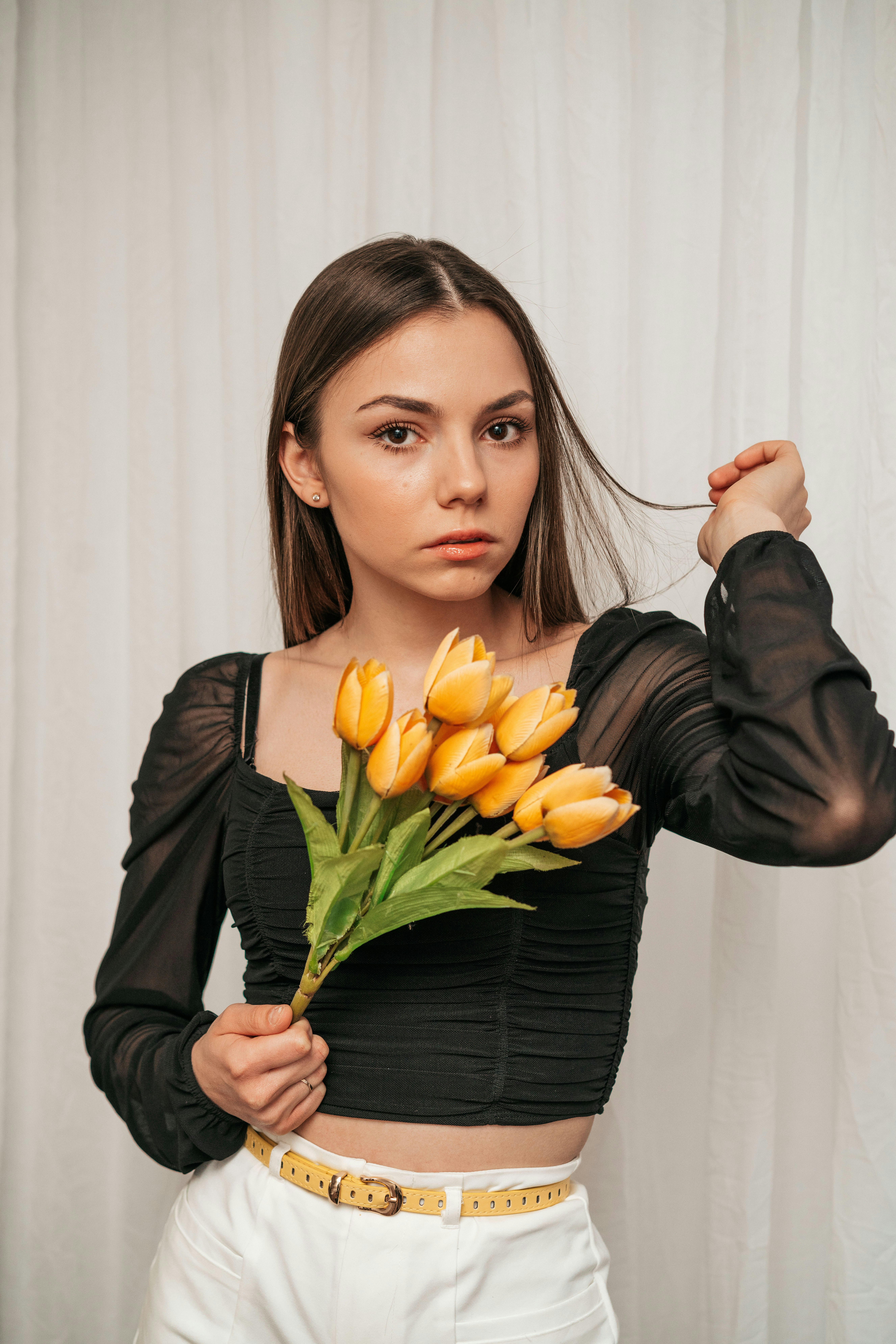 woman in black long sleeve shirt holding yellow tulips