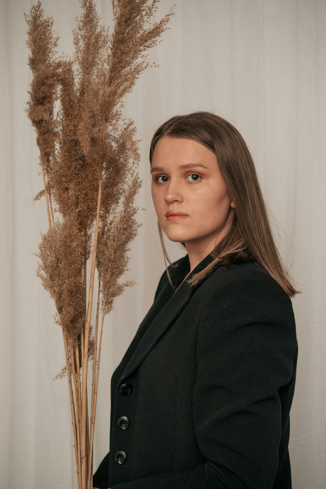 woman in black coat standing near brown plant