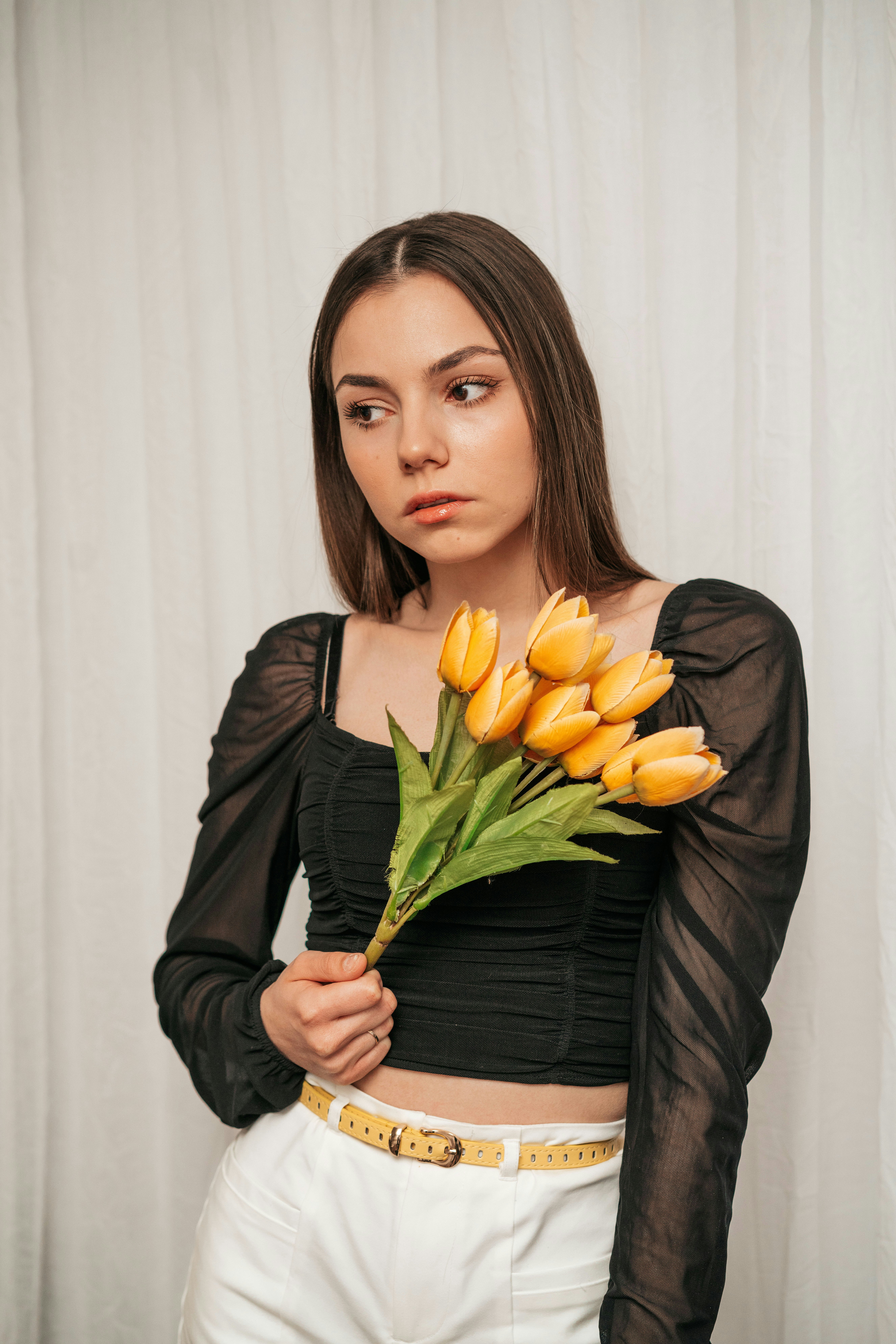 woman in black long sleeve shirt holding yellow tulips