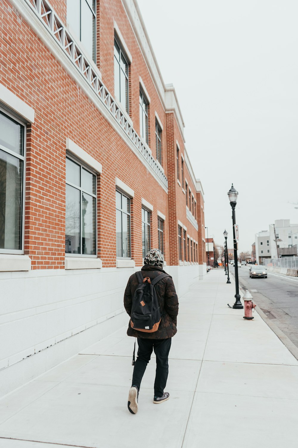 person in black jacket walking on sidewalk during daytime