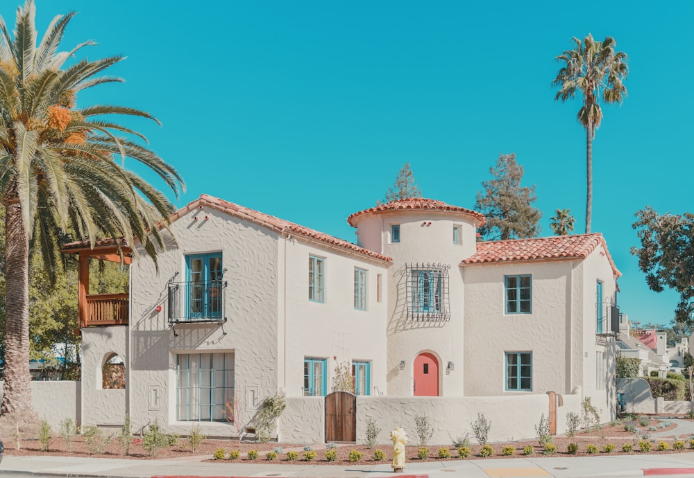 white and pink concrete building near palm trees under blue sky during daytime