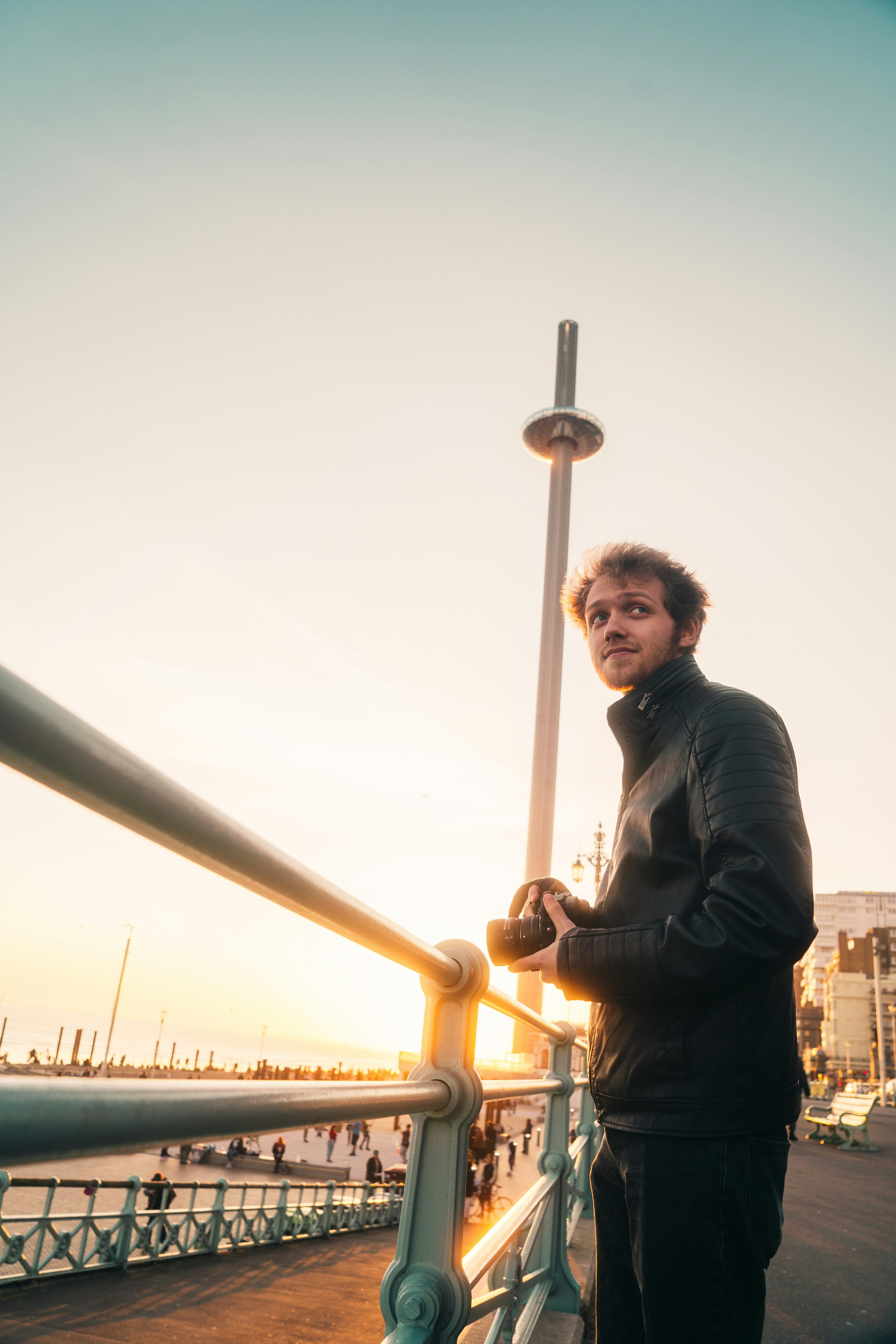 man in black jacket standing beside yellow metal railings during daytime