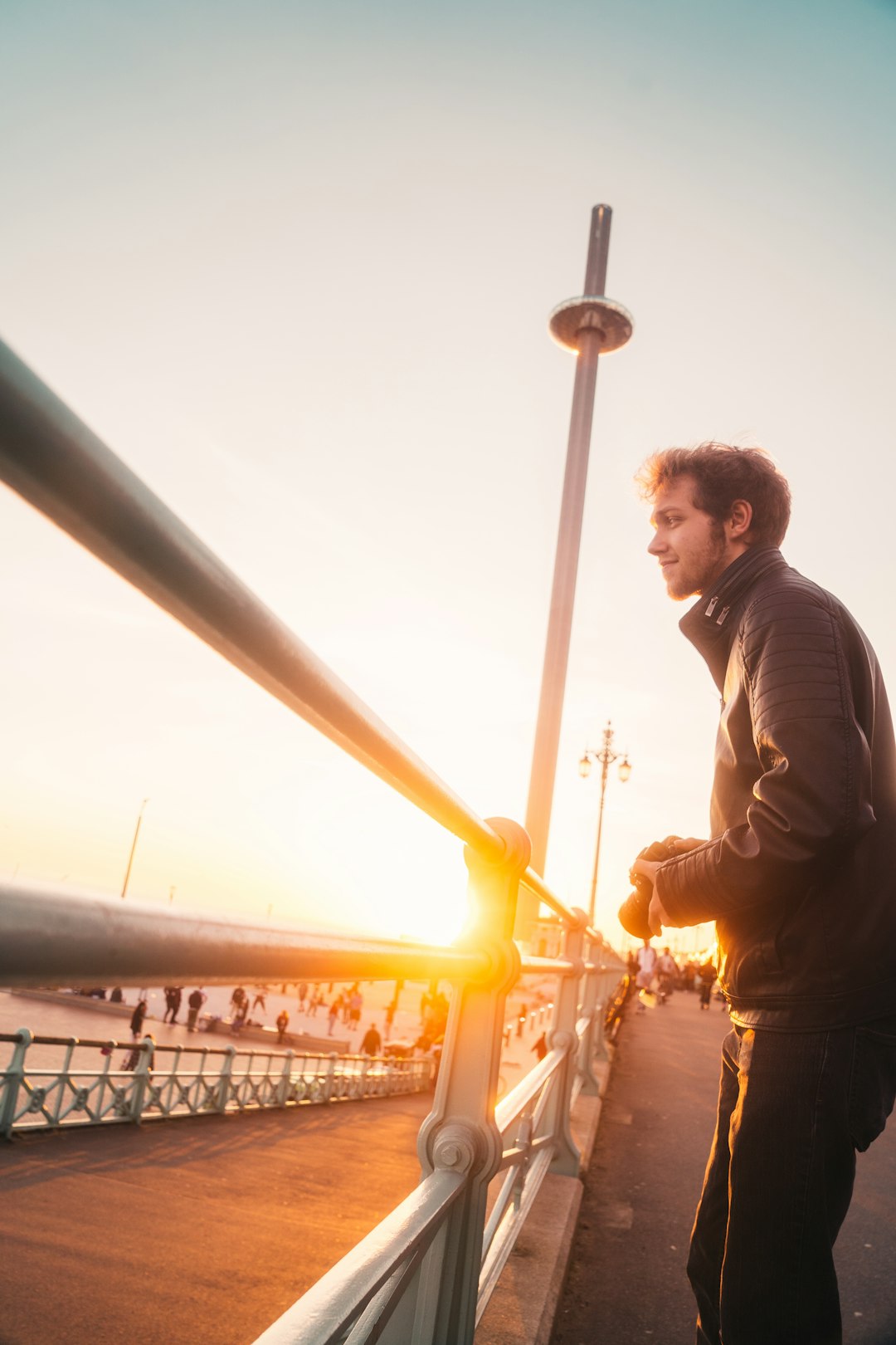 man in black jacket standing near yellow metal post during daytime