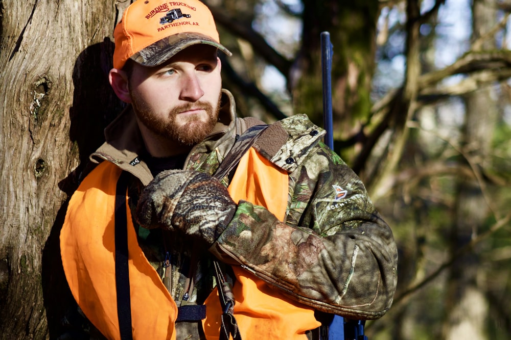 man in green and brown camouflage jacket wearing orange and black backpack