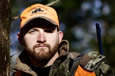 man in orange and black zip up jacket and orange cap