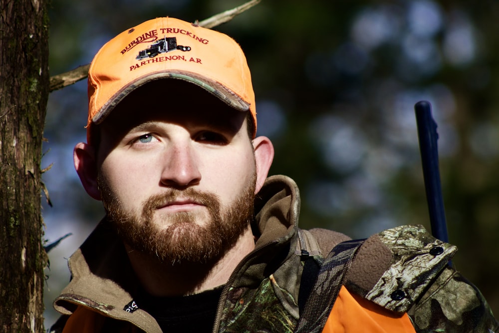 man in orange and black zip up jacket and orange cap