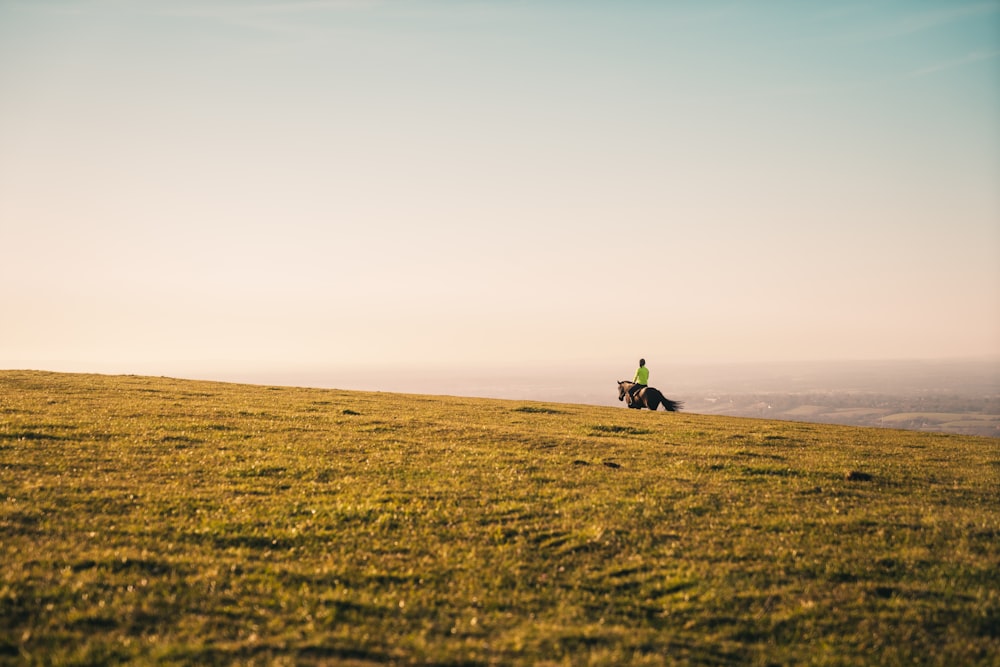 person in green jacket walking on brown field during daytime