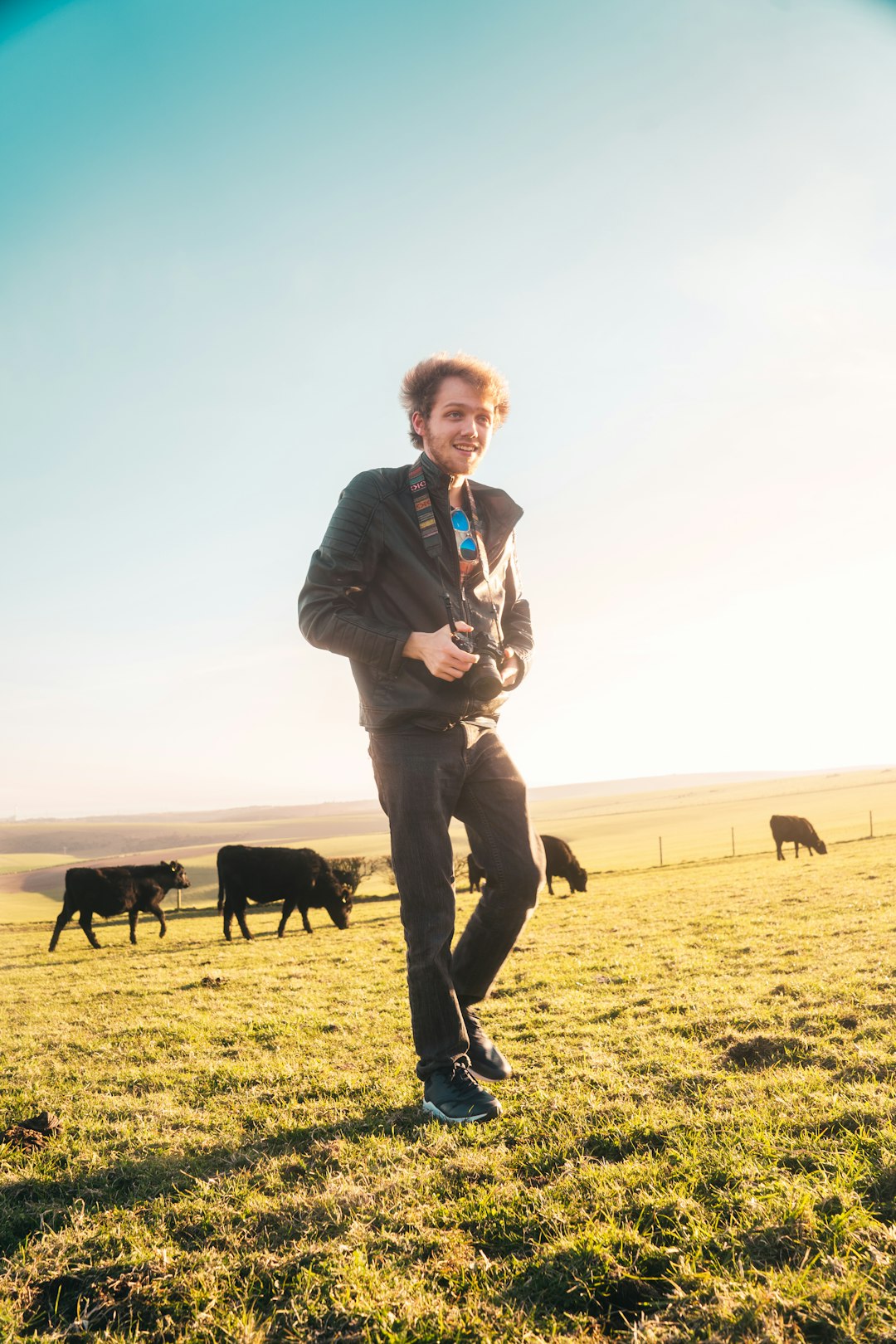 man in black jacket and black pants standing on green grass field with black dog during