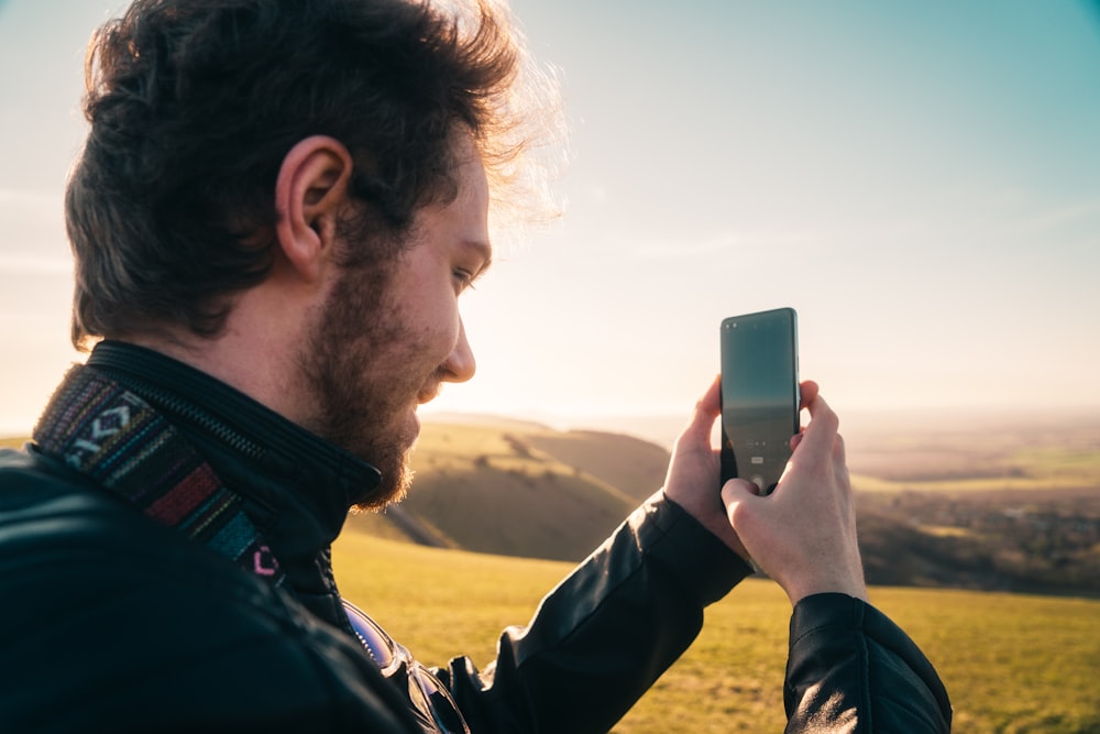 man in black jacket holding iphone during daytime