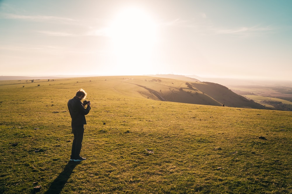 man in black jacket standing on green grass field during daytime