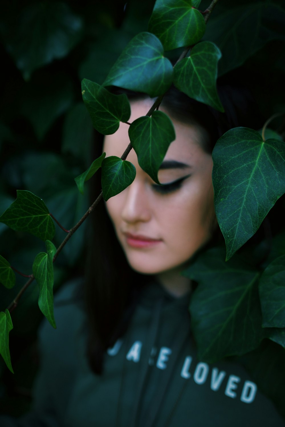 woman in black shirt hiding behind green leaves