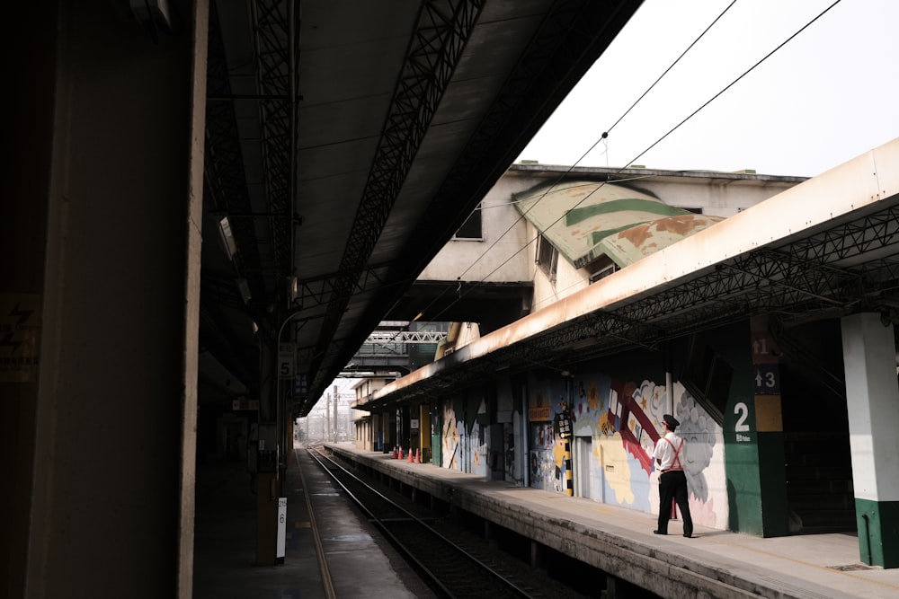 man in white shirt and black pants walking on train station