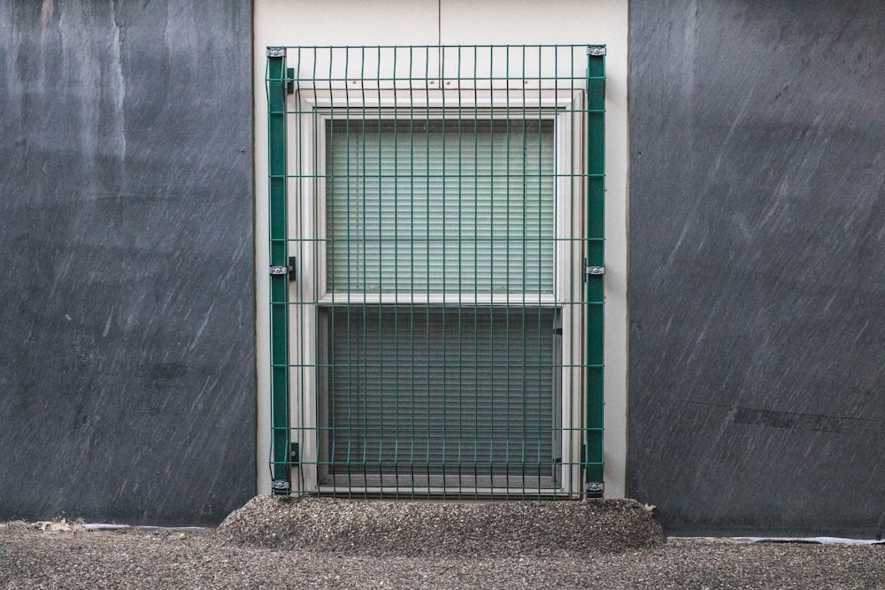 green metal gate on gray concrete wall