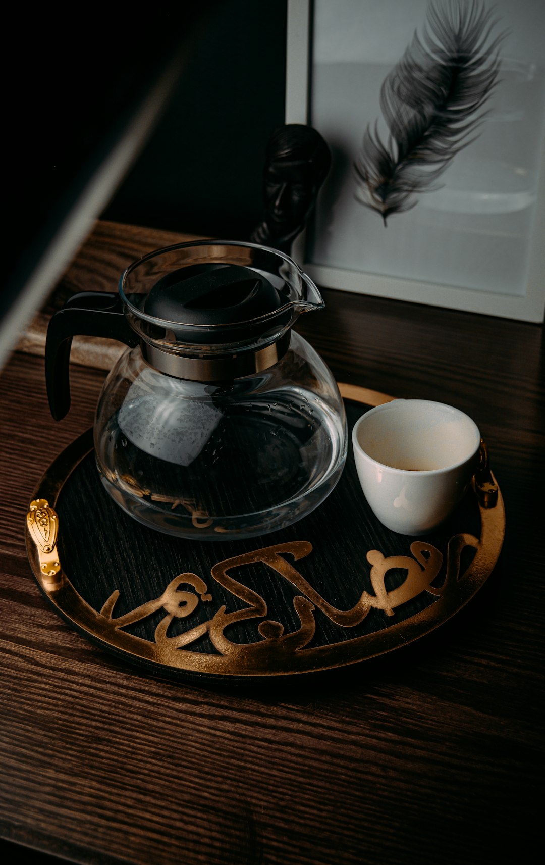 clear glass teapot beside white ceramic teacup on brown wooden table