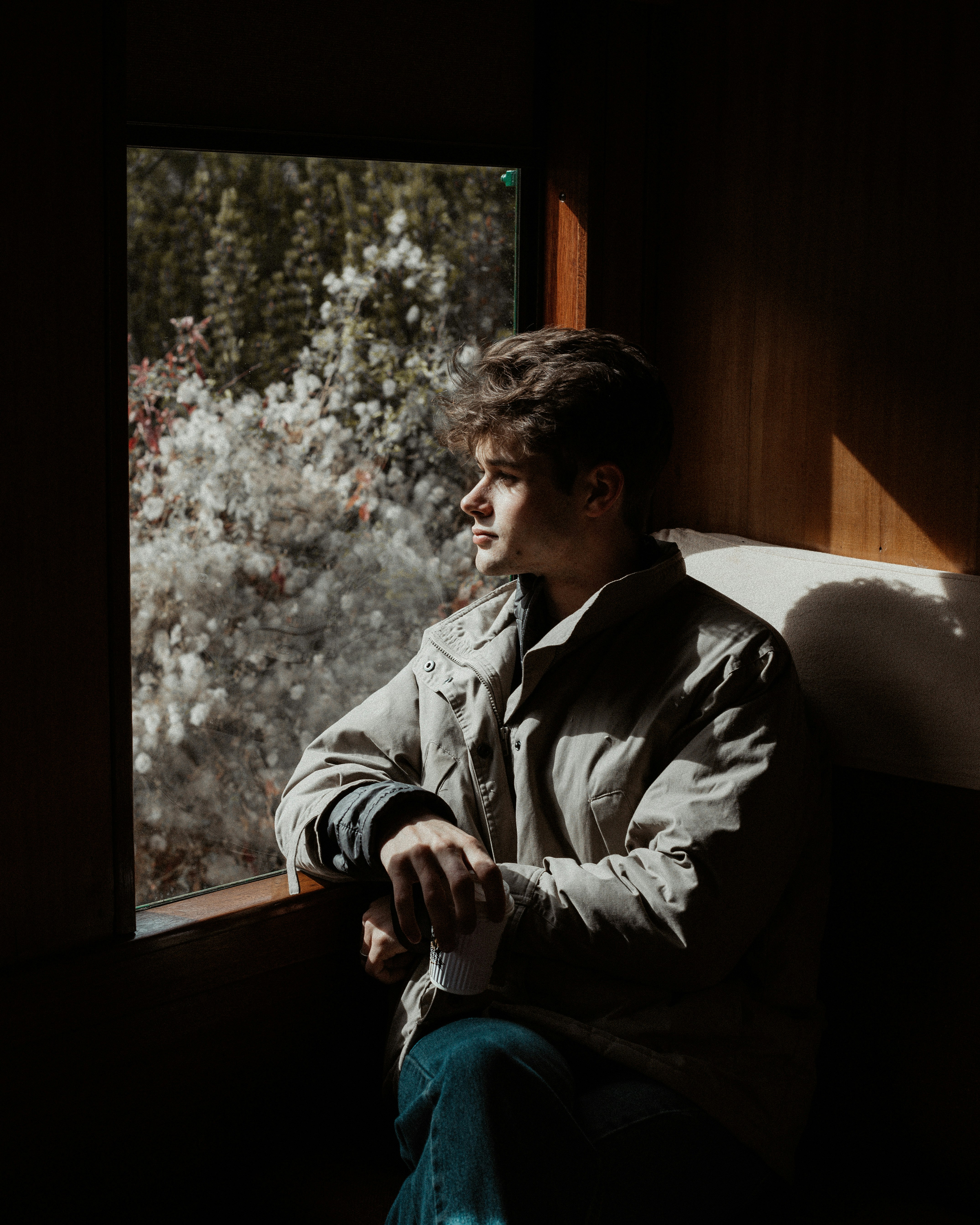 man in gray jacket sitting on window