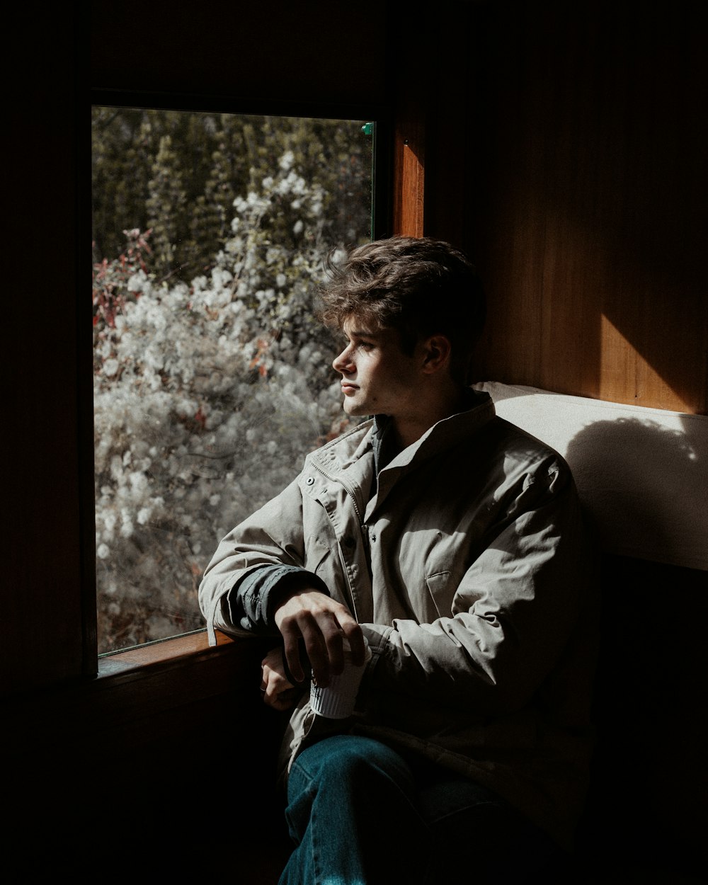 man in gray jacket sitting on window