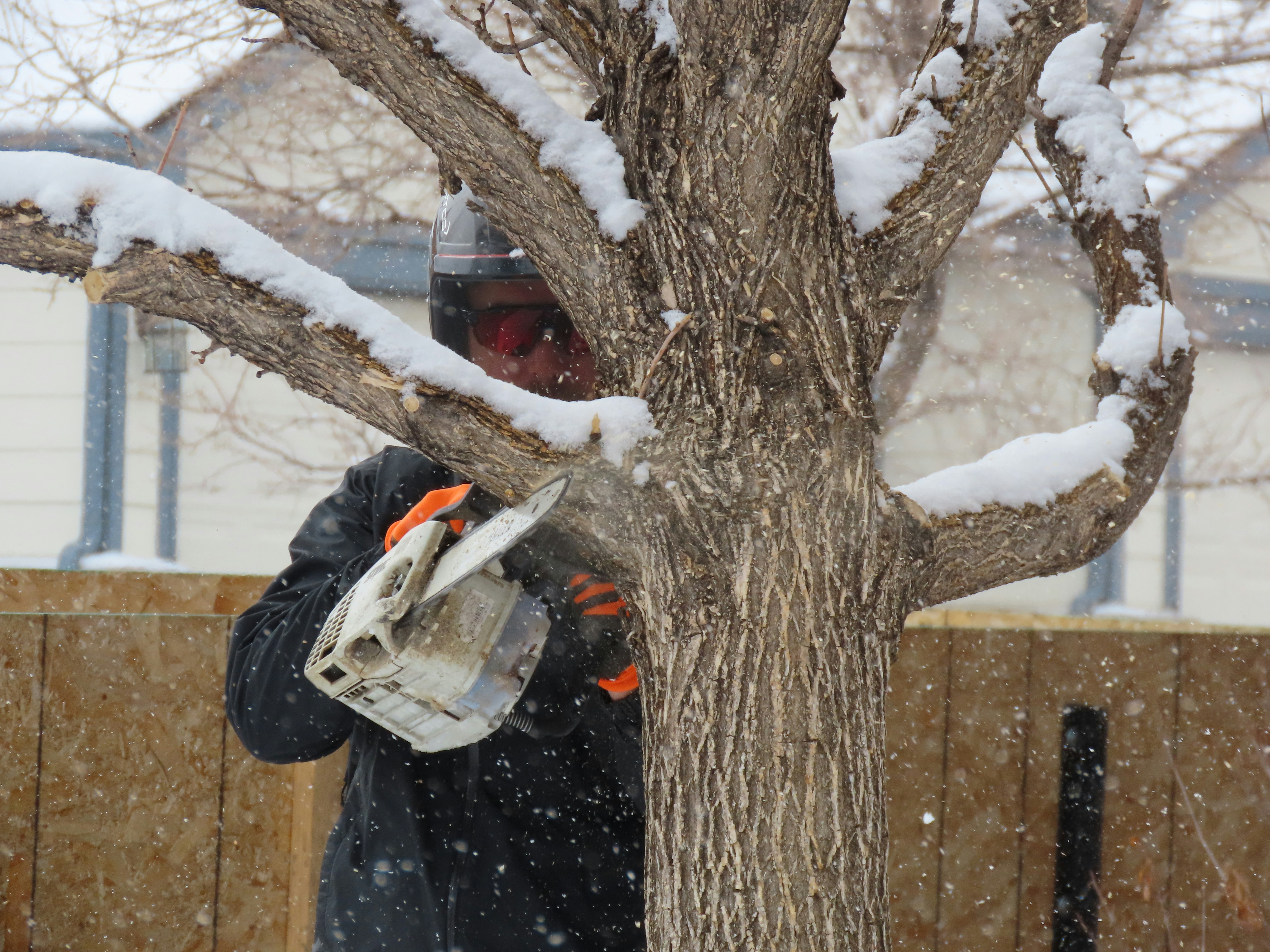 person in black jacket and gray pants holding orange snow shovel