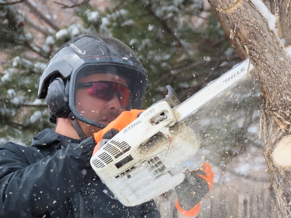 man in black jacket holding orange and white snow blower