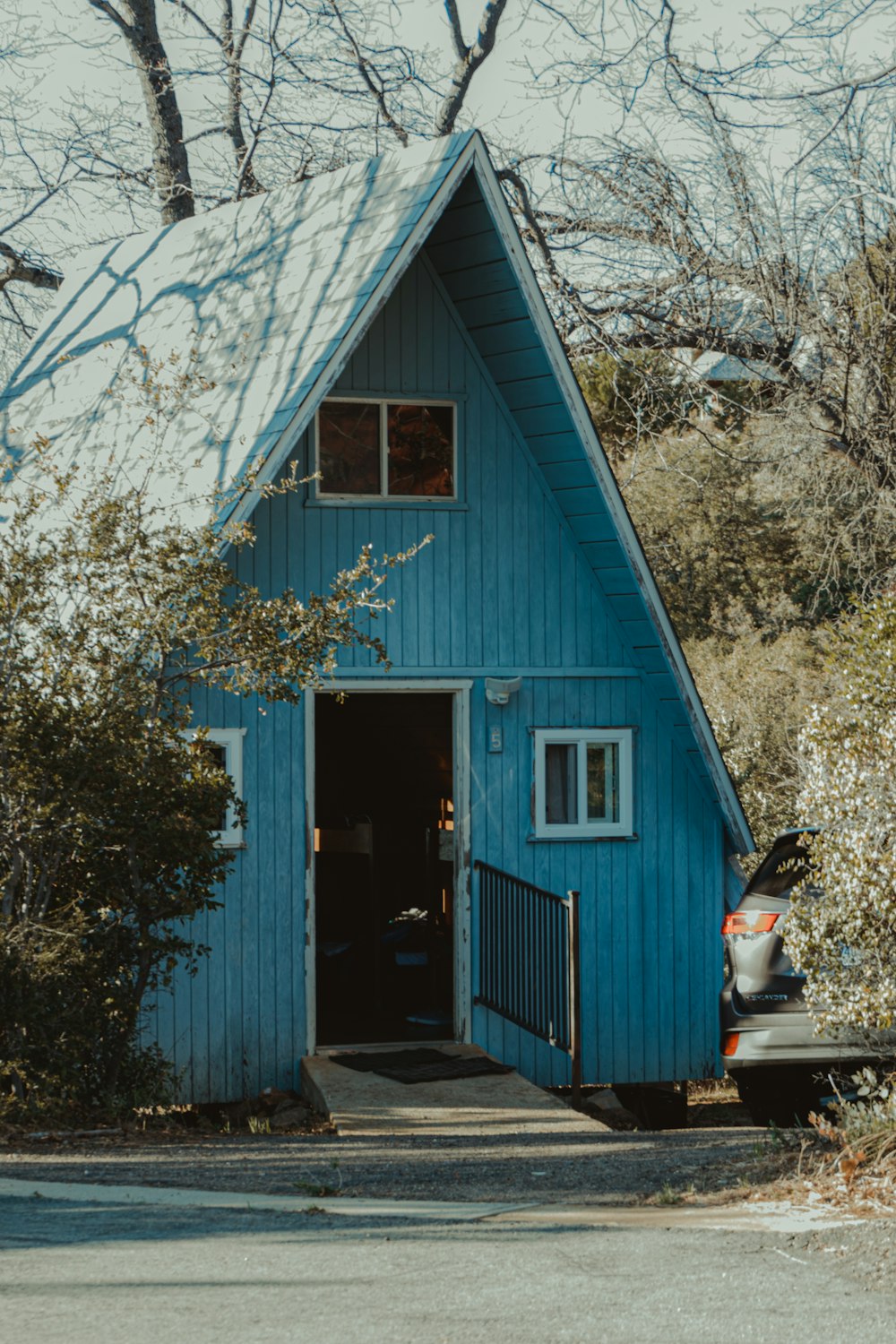 blue wooden house near trees during daytime