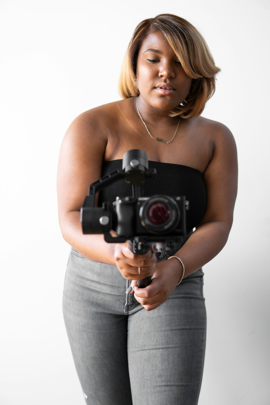 woman in gray tank top holding black dslr camera
