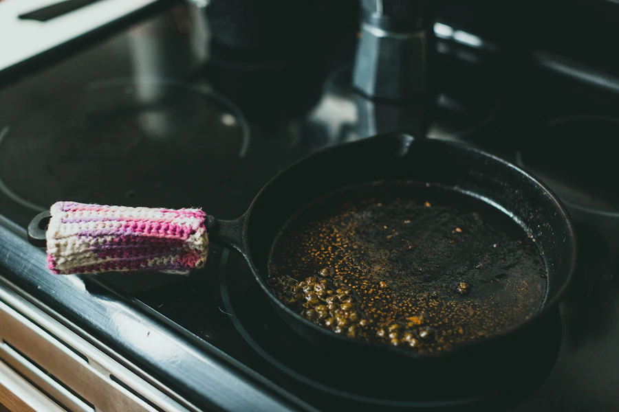 A dark, well-scratched frying pan on a lit stovetop burner