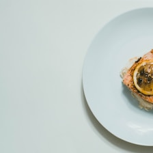 Elegant plated seared salmon garnished with fresh herbs and lemon slices on a minimalist white dish.