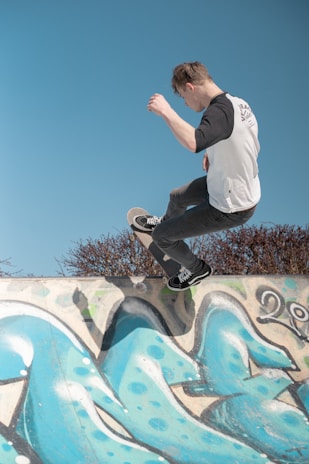 A skateboarder performing tricks on a graffiti-covered ramp.