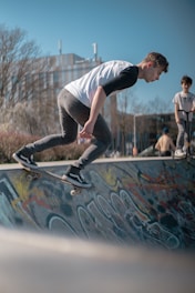 Young athletes practicing skateboarding tricks on an outdoor ramp under clear skies.