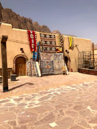 Richly colored carpets laid out on sandy terrain at the rally site.