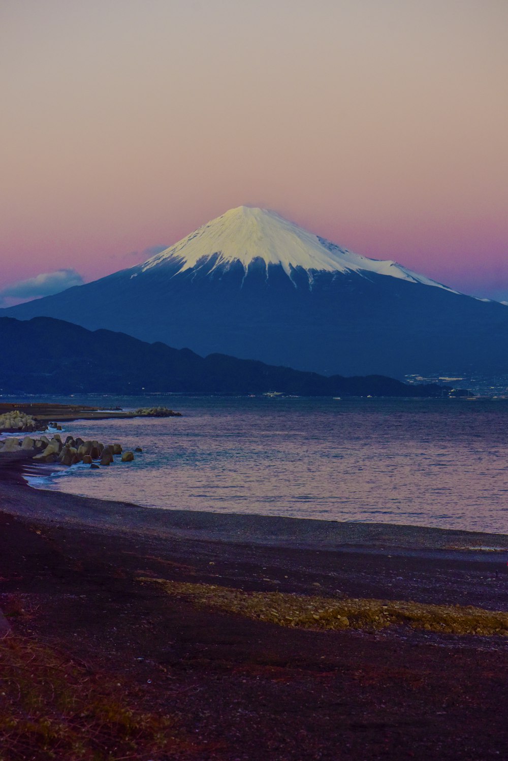 昼間の白い雲の下の山の近くの茶色の砂浜