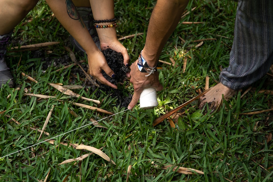 person in black and white shorts holding white plastic bottle, People building temazcal tent