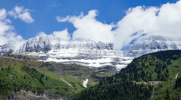 Green trees on mountain under white clouds and blue sky during daytime — Glacier National Park, United States